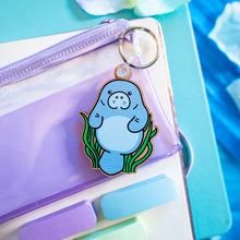 Load image into Gallery viewer, A charming wooden keychain featuring a cute manatee floating serenely in the water. This eco-friendly keychain has a natural, hand-carved design, perfect for adding a touch of ocean love to your keys or bag! 🌊🐘✨