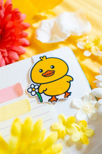 Load image into Gallery viewer, The "Duck with Flowers" magnetic bookmark is a charming and functional accessory for readers. It features a cute duck adorned with flowers, adding a touch of whimsy to your reading experience. The bookmark is double-sided, with a laminate on the front for protection and a glossy finish. Measuring approximately 2.4 inches on its longest side, it comes with a baby blue backing card. The strong magnets securely grip the pages of your book, ensuring you can easily return to where you left off