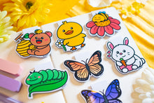 Load image into Gallery viewer, The "Duck with Flowers" magnetic bookmark is a charming and functional accessory for readers. It features a cute duck adorned with flowers, adding a touch of whimsy to your reading experience. The bookmark is double-sided, with a laminate on the front for protection and a glossy finish. Measuring approximately 2.4 inches on its longest side, it comes with a baby blue backing card. The strong magnets securely grip the pages of your book, ensuring you can easily return to where you left off