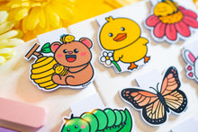 Load image into Gallery viewer, A cute bookmark featuring a bear with a bee buzzing around it, and a detailed beehive in the background. The design is playful and charming, perfect for marking your place in a book