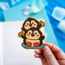 Load image into Gallery viewer, An adorable bamboo sticker featuring two playful penguin twins, standing side by side with cheerful expressions. This eco-friendly sticker has a cute, hand-drawn style, perfect for decorating laptops, water bottles, and notebooks! 🐧💙✨