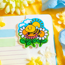 Load image into Gallery viewer, A Spring Bee Magnetic Bookmark is a charming accessory designed to mark your place in books, planners, or journals. Featuring a delightful bee illustration, this bookmark adds a touch of whimsy to your reading experience. Its strong magnets securely grip the pages, ensuring you can easily return to your spot.
