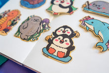 Load image into Gallery viewer, An adorable bamboo sticker featuring two playful penguin twins, standing side by side with cheerful expressions. This eco-friendly sticker has a cute, hand-drawn style, perfect for decorating laptops, water bottles, and notebooks! 🐧💙✨
