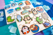 Load image into Gallery viewer, A bamboo keychain shaped like a crocodile, showcasing a detailed yet minimalist design. The crocodile features etched scales, a long snout, and a playful grin, all engraved into the natural bamboo material. The smooth wood grain adds a rustic and eco-friendly charm, while the compact size makes it perfect for keys, backpacks, or purses