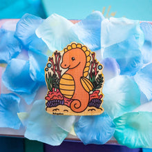 Load image into Gallery viewer,   A charming bamboo sticker featuring a regal seahorse adorned with a tiny crown, floating gracefully in the ocean. This eco-friendly sticker has a whimsical, hand-drawn style, perfect for decorating laptops, water bottles, and journals! 👑🐉✨