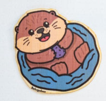 Load image into Gallery viewer, A cute sea otter floating happily on its back, holding a seashell with a cheerful expression. This eco-friendly bamboo sticker features a charming, hand-drawn style, perfect for decorating laptops, water bottles, and journals! 🦦💙✨