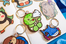 Load image into Gallery viewer, A wooden shark keychain is a handcrafted accessory that combines functionality with a touch of marine-inspired artistry. Typically made from sustainable woods like maple or cherry veneer, these keychains are lightweight and durable. They often feature laser-engraved designs, showcasing intricate details of shark species. The natural wood finish provides a rustic aesthetic, making them a unique gift for ocean enthusiasts or a stylish addition to your personal items.