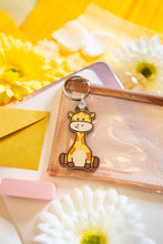 Load image into Gallery viewer, A delightful wooden keychain featuring a cute giraffe with a long neck and a friendly smile. This eco-friendly keychain has a charming, hand-carved design, perfect for adding a touch of jungle-inspired fun to your keys or bag! 🦒🌿✨