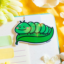 Load image into Gallery viewer, A charming magnetic bookmark featuring an adorable caterpillar design. The caterpillar is illustrated in a playful, cartoonish style with a series of bright, colorful segments and a happy, smiling face. Its whimsical details, like tiny antennae and cheerful eyes, make it a fun companion for any book. The fold-over magnetic closure keeps it securely in place, making it both practical and delightful for marking your pages. Perfect for book lovers and fans of cute critters!