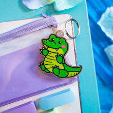 Load image into Gallery viewer, A bamboo keychain shaped like a crocodile, showcasing a detailed yet minimalist design. The crocodile features etched scales, a long snout, and a playful grin, all engraved into the natural bamboo material. The smooth wood grain adds a rustic and eco-friendly charm, while the compact size makes it perfect for keys, backpacks, or purses