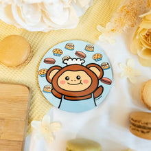 Load image into Gallery viewer, "Baby Blue Monkey Cozy Cafe Coaster featuring a playful monkey surrounded by delicious treats, including muffins, cinnamon rolls, and colorful macarons, perfect for adding a touch of fun to your coffee table."