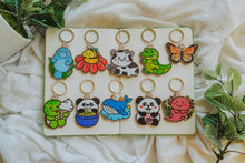 Load image into Gallery viewer, Variety of Wooden Keychains - Explore a collection of delightful wooden keychains, featuring adorable animal designs like manatees, pandas, cows, and more. Elevate your accessories with these vibrant and eco-friendly charms. 🌈🔑 #WoodenKeychains #EcoFriendlyAccessories #CharmingAnimals