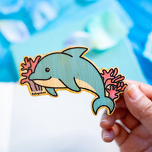 Load image into Gallery viewer, A bamboo sticker featuring a sleek and playful dolphin design. The dolphin is depicted mid-jump, with smooth curves and a cheerful expression, surrounded by subtle water splash details. The natural bamboo texture adds an eco-friendly touch, with the dolphin's design standing out in vibrant shades of blue and gray. Perfect for decorating water bottles, laptops, or notebooks.