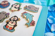 Load image into Gallery viewer, A bamboo sticker featuring a sleek and playful dolphin design. The dolphin is depicted mid-jump, with smooth curves and a cheerful expression, surrounded by subtle water splash details. The natural bamboo texture adds an eco-friendly touch, with the dolphin's design standing out in vibrant shades of blue and gray. Perfect for decorating water bottles, laptops, or notebooks.