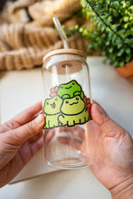 Load image into Gallery viewer, Belugabee Bamboo Sticker: Whimsical scene of three frogs surrounded by vibrant lily flowers, enhancing the charm of your glass cup. Elevate your style with this eco-friendly and delightful 3x3-inch bamboo sticker. 🐸🌸 #BambooSticker #FrogAndLilies #GlassCupDecor