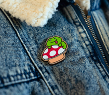 Load image into Gallery viewer, A whimsical wooden pin featuring a cute frog sitting on a mushroom, surrounded by tiny natural details. This eco-friendly pin has a charming, hand-carved design, perfect for adding a touch of nature-inspired magic to your bag or jacket! 🐸🍄✨