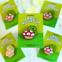Load image into Gallery viewer, A whimsical wooden pin featuring a cute frog sitting on a mushroom, surrounded by tiny natural details. This eco-friendly pin has a charming, hand-carved design, perfect for adding a touch of nature-inspired magic to your bag or jacket! 🐸🍄✨