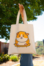 Load image into Gallery viewer, A cute and cuddly guinea pig sitting happily with a cheerful expression, surrounded by soft greenery. This eco-friendly tote bag features a playful, hand-drawn design, perfect for guinea pig lovers and everyday use! 🐹💚✨