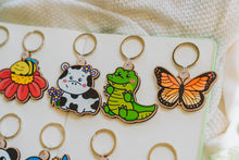 Load image into Gallery viewer, Close-up shot capturing the details of the Monarch Butterfly Keychain, elegantly displayed alongside a Crocodile and Cow with Flowers keychain. 🦋🐊🌸 #NatureInspiredAccessories #WoodenKeychains #CharmingCollection