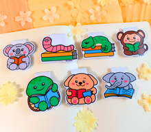 Load image into Gallery viewer, A playful magnetic bookmark featuring a curious monkey reading a book with a big smile. This eco-friendly bookmark has a fun, hand-drawn style, perfect for adding a touch of jungle joy to your reading! 🐒📖✨