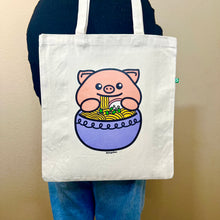 Load image into Gallery viewer, An adorable design featuring a happy pig enjoying a big bowl of ramen, complete with noodles, chopsticks, and tasty toppings! Printed on a durable, eco-friendly tote bag, perfect for carrying books, groceries, and daily essentials. A must-have for foodies and pig lovers alike!