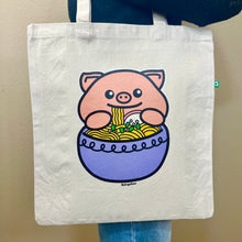 Load image into Gallery viewer, An adorable design featuring a happy pig enjoying a big bowl of ramen, complete with noodles, chopsticks, and tasty toppings! Printed on a durable, eco-friendly tote bag, perfect for carrying books, groceries, and daily essentials. A must-have for foodies and pig lovers alike!