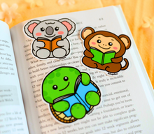 Load image into Gallery viewer, A glossy sticker featuring a turtle reading a book, available on Redbubble