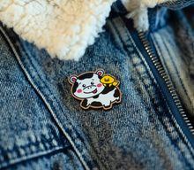 Load image into Gallery viewer, 
A wooden pin featuring an adorable design of a cow and a duck together. The cow, with a friendly and calm expression, is etched with fine details like spots and a subtle wood grain texture. The duck sits cheerfully on the cow's back, adding a playful touch to the design. The natural wood finish gives the pin a rustic, eco-friendly charm, perfect for accessorizing jackets, bags, or hats