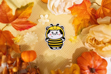 Load image into Gallery viewer, A cute sticker featuring a cow dressed in a bee costume. The cow has a cheerful expression, wearing yellow and black stripes, tiny wings, and a pair of antennae with small round tips. The design is cartoonish and playful, with the cow's spots and hooves adding to its charm. Perfect for adding a whimsical touch to water bottles, laptops, or notebooks.