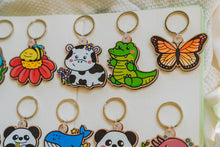 Load image into Gallery viewer, A bamboo keychain shaped like a crocodile, showcasing a detailed yet minimalist design. The crocodile features etched scales, a long snout, and a playful grin, all engraved into the natural bamboo material. The smooth wood grain adds a rustic and eco-friendly charm, while the compact size makes it perfect for keys, backpacks, or purses
