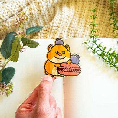 Belugabee Hamster Macaron Bamboo Sticker Alt Text: Cute hamster holding a macaroon with a playful blueberry perched on its head, intricately designed on eco-friendly bamboo. 🐹🍬 #BambooSticker #HamsterMacaronDesign #AdorableDecor