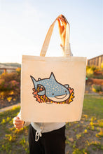 Load image into Gallery viewer, The Whale Shark Tote Bag is a stylish and eco-friendly accessory that showcases a beautifully detailed design of the gentle giant of the sea: the whale shark. Made from 100% organic cotton, this tote bag is perfect for marine life enthusiasts or those who appreciate the beauty of nature. Its spacious interior provides ample room for carrying essentials, making it ideal for beach outings, grocery shopping, or daily use. The sturdy construction ensures durability, while the soft fabric offers comfort and flex