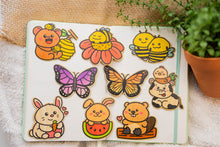 Load image into Gallery viewer, Bamboo Sticker Collection - A captivating array of nine distinct bamboo stickers, each contributing its unique charm and eco-friendly appeal, beautifully arranged on a notebook.