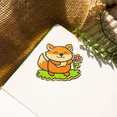 Belugabee Bamboo Sticker: Adorable fox smiling on grass, delicately holding a pink flower. Elevate your style with this charming 3x3-inch eco-friendly bamboo sticker. 🦊🌸 #BambooSticker #FoxDesign #NatureInspiredArt