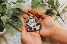Load image into Gallery viewer, Belugabee Cow and Flowers Wooden Keychain: Adorable solo keychain featuring a happy cow amidst vibrant purple flowers. Elevate your accessories with this eco-friendly wooden charm. 🐮🌸🔑 #WoodenKeychain #CowAndFlowers #NatureInspiredAccessories
