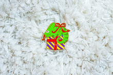 Load image into Gallery viewer, Chameleon Holiday Hard Enamel Pin: Adorable green chameleon perched on a gift with a festive wrapping bow. Elevate your style with this limited edition accessory. 🦎🎁 #ChameleonPin #HolidayEnamelPin #GiftWrappedChameleon
