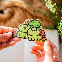 Load image into Gallery viewer, Whimsical scene of three frogs surrounded by vibrant lily flowers, crafted on eco-friendly bamboo. Elevate your style with this charming 3x3-inch sticker. 🐸🌸 #BambooSticker #FrogAndLilies #NatureInspiredArt
