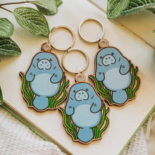 Load image into Gallery viewer, Manatee Wooden Keychain Trio - Three adorable manatee keychains in a row, showcasing the same delightful underwater design. 🌊🦭 #ManateeKeychain #OceanCharm #WoodenAccessories

