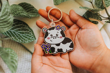Load image into Gallery viewer, Belugabee Cow and Flowers Wooden Keychain: Adorable solo keychain featuring a happy cow amidst vibrant purple flowers. Elevate your accessories with this eco-friendly wooden charm. 🐮🌸🔑 #WoodenKeychain #CowAndFlowers #NatureInspiredAccessories
