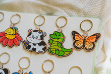 Load image into Gallery viewer, Close-up shot capturing the details of the Monarch Butterfly Keychain, elegantly displayed alongside a Crocodile and Cow with Flowers keychain. 🦋🐊🌸 #NatureInspiredAccessories #WoodenKeychains #CharmingCollection
