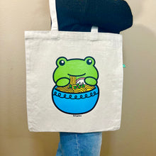 Load image into Gallery viewer, Belugabee Frog Ramen Tote Bag: Whimsical design of a frog slurping noodles from a blue ramen bowl, adding charm to your eco-friendly tote. 🐸🍜🛍️ #FrogRamenToteBag #HumorousDesign #EcoFriendlyFashion
