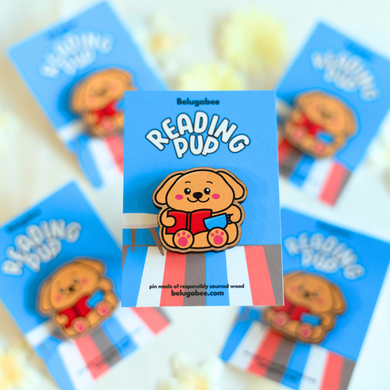 A charming wooden pin featuring a cute puppy with glasses, deeply focused on reading a book. This eco-friendly pin has a delightful, hand-carved design, perfect for adding a touch of puppy love to your accessories! 🐶📖✨