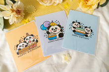 Load image into Gallery viewer, A charming birthday card featuring adorable pandas, each with a joyful expression, surrounding a delicious-looking cupcake topped with colorful frosting and a candle. The card includes the message &quot;Happy Birthday&quot; in playful, vibrant lettering, adding a festive touch to the celebration

