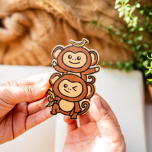 Load image into Gallery viewer, Playful Monkey Twins Bamboo Sticker features two adorable monkeys stacked on top of each other, each joyfully holding a banana. Add a touch of whimsy to your belongings with this delightful bamboo sticker. 🐒🍌 #MonkeyTwins #BambooSticker #PlayfulCharm
