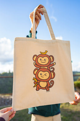 A playful design featuring two adorable monkey twins hanging from a leafy branch, their tails curled together in a sweet embrace. Printed on a durable, eco-friendly tote bag, perfect for carrying books, groceries, and daily essentials. A fun and charming choice for monkey lovers