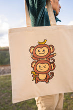 Load image into Gallery viewer, A playful design featuring two adorable monkey twins hanging from a leafy branch, their tails curled together in a sweet embrace. Printed on a durable, eco-friendly tote bag, perfect for carrying books, groceries, and daily essentials. A fun and charming choice for monkey lovers
