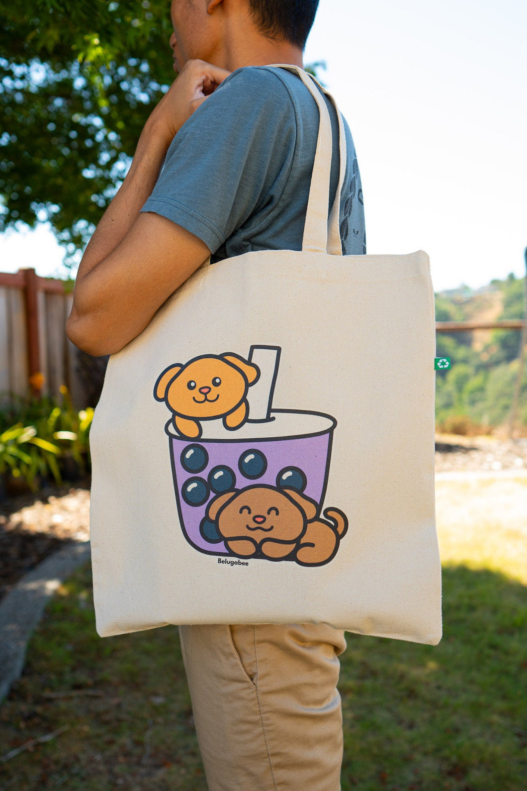 A super cute tote bag featuring playful puppies peeking out of a boba tea cup, surrounded by tapioca pearls. This eco-friendly bag has a fun, hand-drawn design, perfect for dog and boba lovers alike! 🐶🧋✨