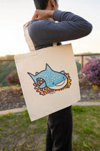 Load image into Gallery viewer, The Whale Shark Tote Bag is a stylish and eco-friendly accessory that showcases a beautifully detailed design of the gentle giant of the sea: the whale shark. Made from 100% organic cotton, this tote bag is perfect for marine life enthusiasts or those who appreciate the beauty of nature. Its spacious interior provides ample room for carrying essentials, making it ideal for beach outings, grocery shopping, or daily use. The sturdy construction ensures durability, while the soft fabric offers comfort and flex
