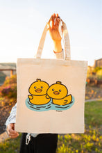 Load image into Gallery viewer, A &quot;duckie&quot; tote bag typically features a playful design centered around a rubber duck, often in bright yellow with a red beak and black eyes. These bags are commonly made from durable materials like canvas or cotton, making them suitable for everyday use.
