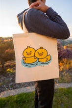 Load image into Gallery viewer, A &quot;duckie&quot; tote bag typically features a playful design centered around a rubber duck, often in bright yellow with a red beak and black eyes. These bags are commonly made from durable materials like canvas or cotton, making them suitable for everyday use.
